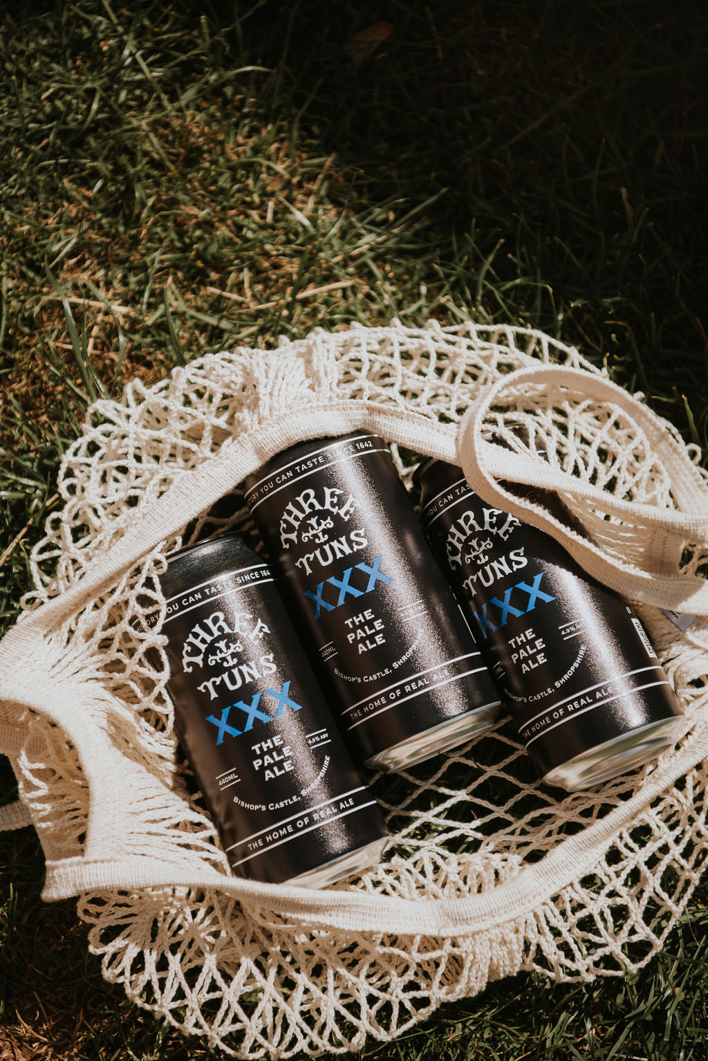 xxx pale ale beer cans in mesh bag on grass three tuns brewery