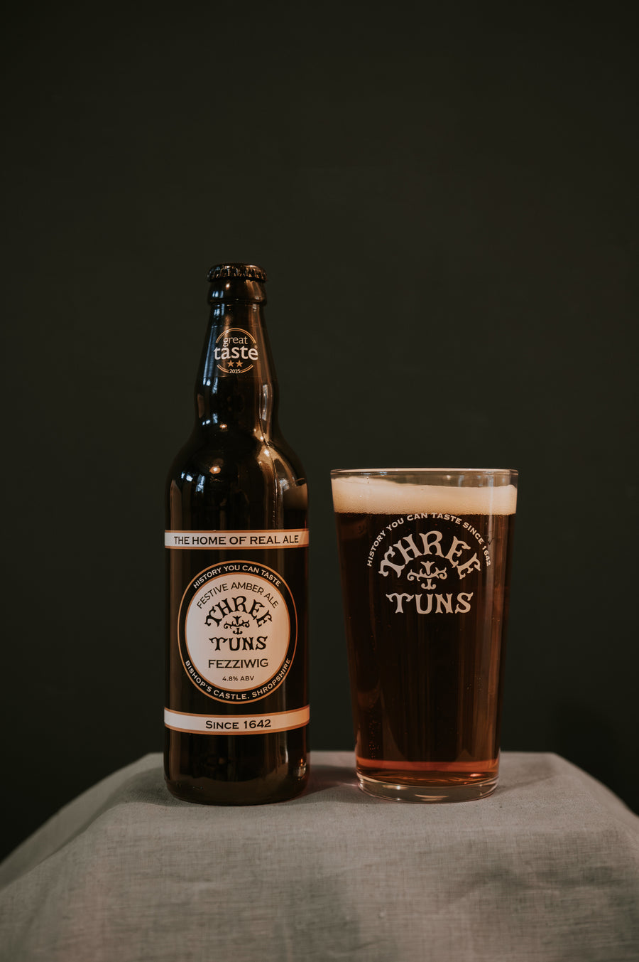 three tuns brewery beer bottle and pint glass of real ale on a dark background