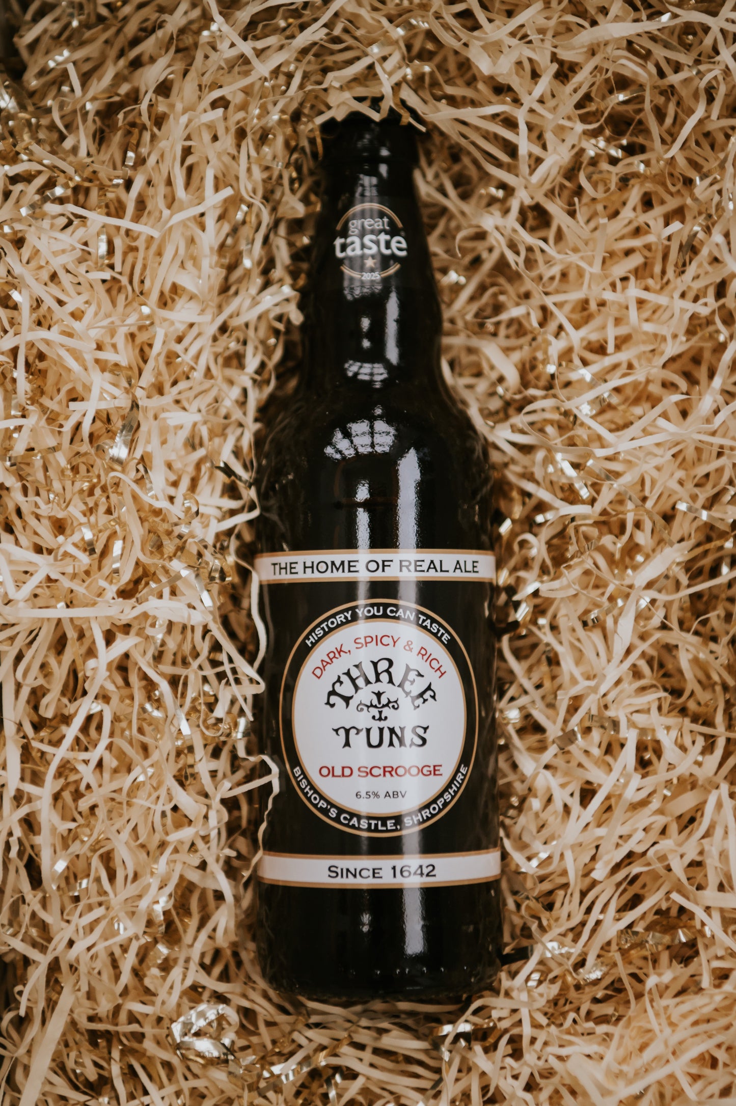 bottle of three tuns brewery old scrooge beer on a bed of hamper straw