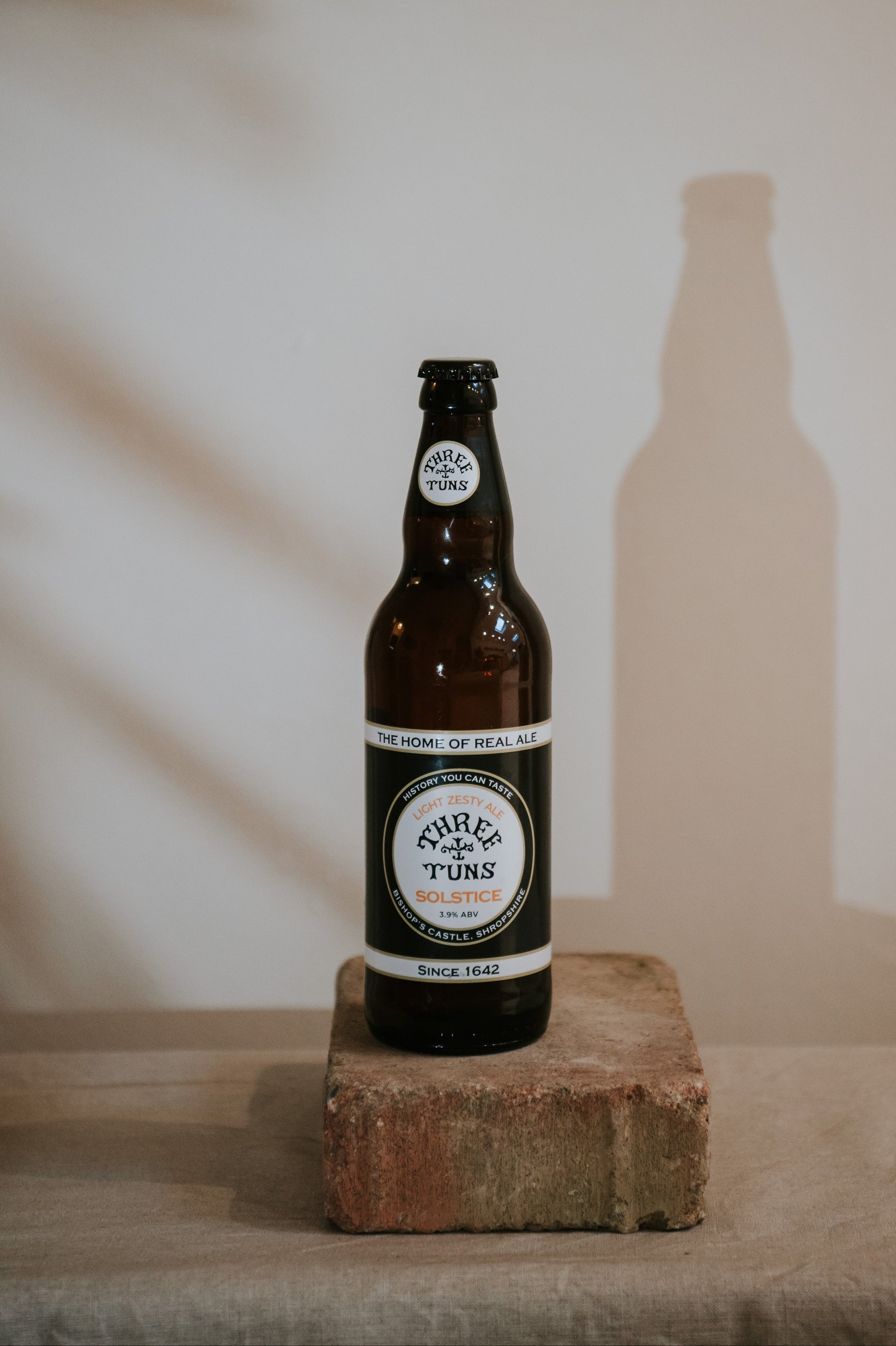 bottle of three tuns brewery solstice beer on concrete plinth