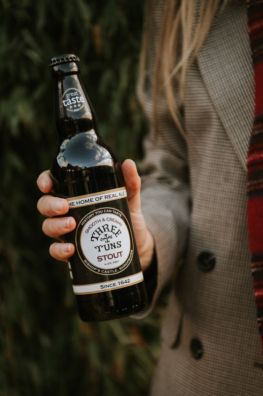 person holding a bottle of three tuns brewery stout ale 